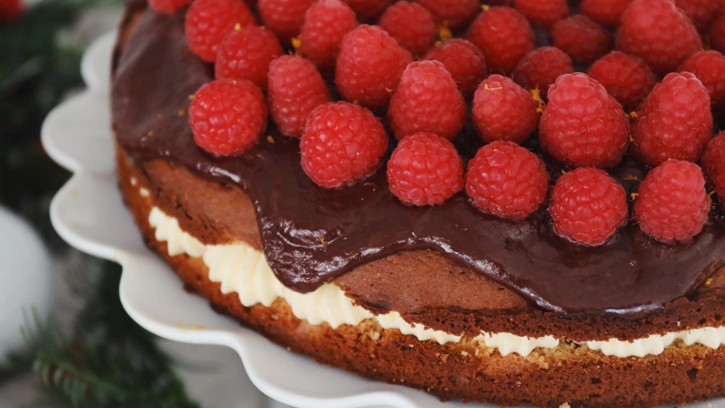 Gâteau au sirop avec de la crème au beurre à l’orange, des framboises et de la ganache